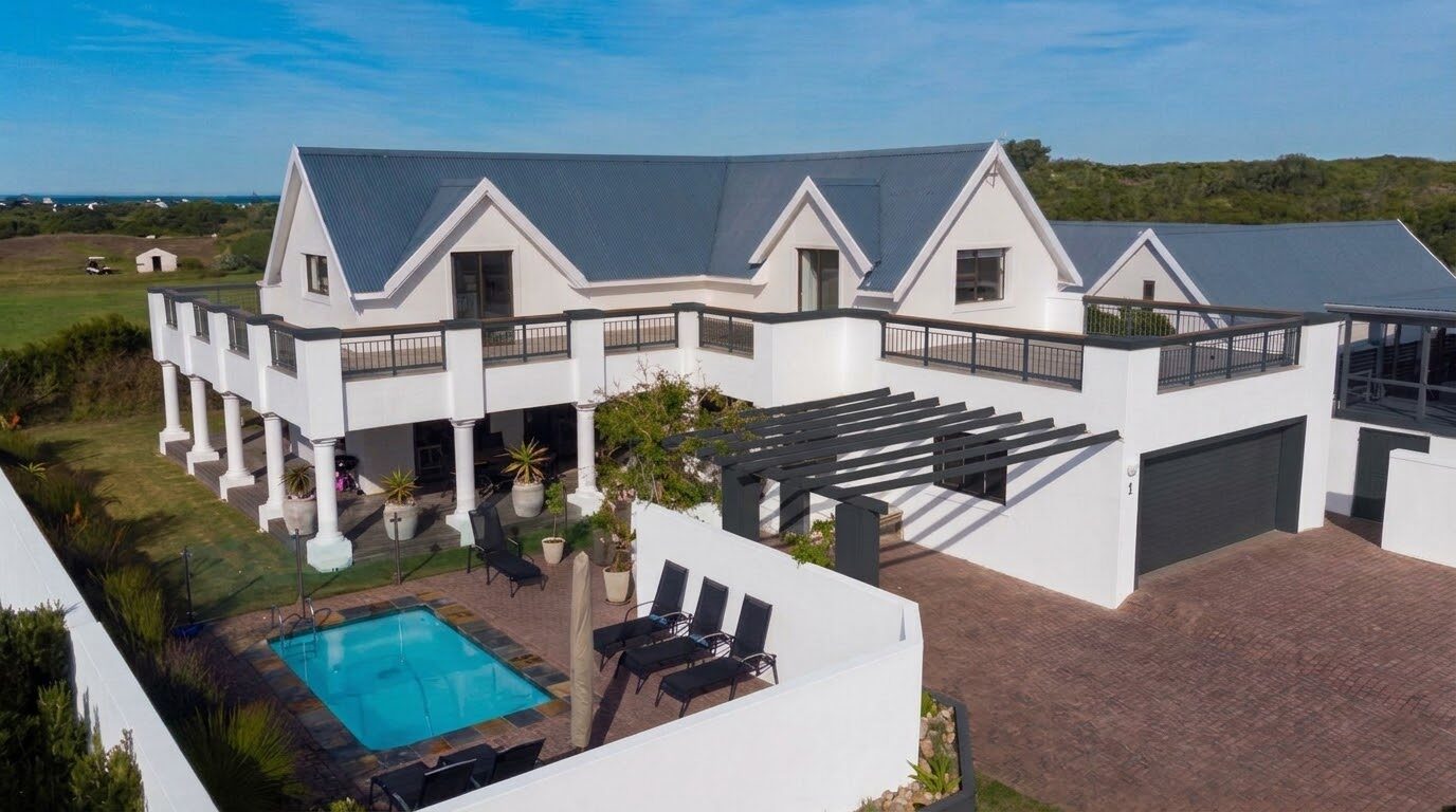 Aerial view of Wildehaven with its charcoal trim, pergola and garage, the pool courtyard, the St Francis Links driving range and the sea beyond